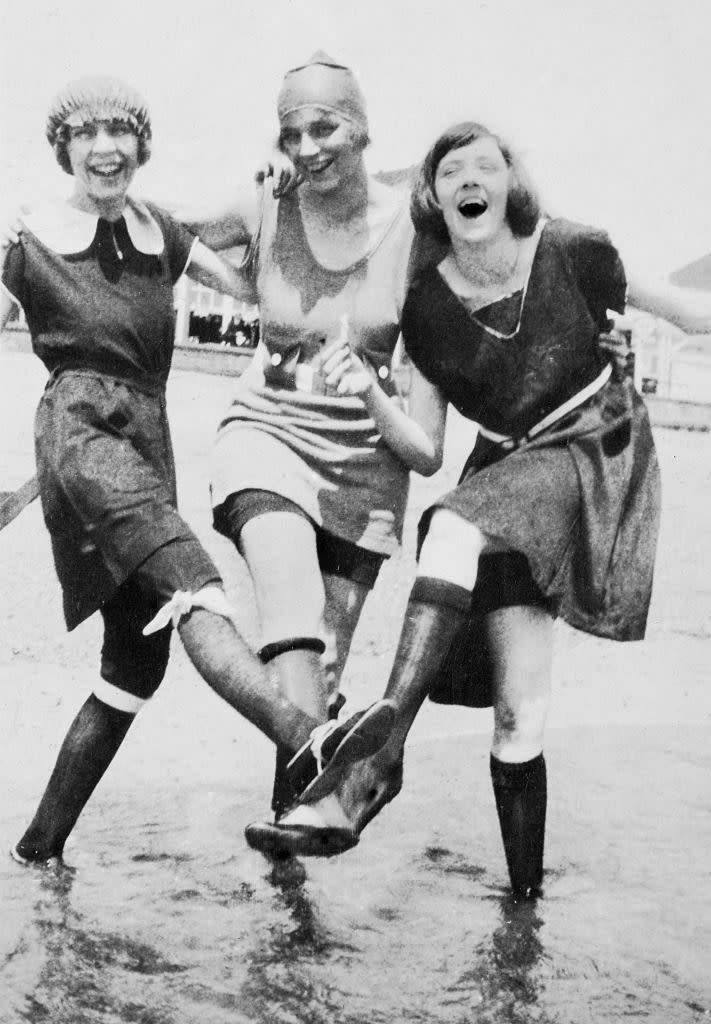 Three teen girls in knee length swim wear splash in the water