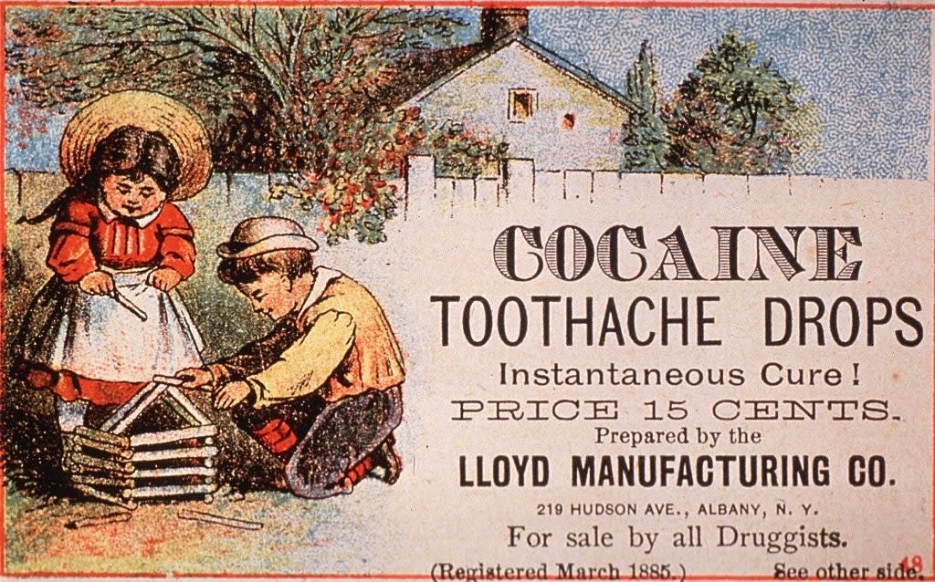 Two children play with a toy house outside; an old advertisement for cocaine toothache drops is displayed, claiming it as an "Instantaneous Cure" for 15 cents