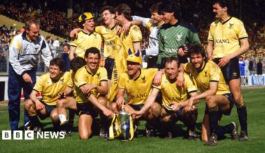 Montage image showing a woman pictured in black and white to the right of the image, wearing a bucket hat and sunglasses, while holding a Welsh flag to the left of the frame