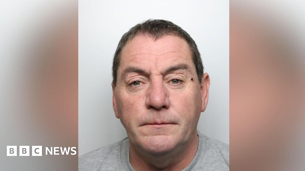 A mugshot of a man in his fifties. He had dark short hair and what appears to be a small cut close to his left eye. He is staring directly into the camera.