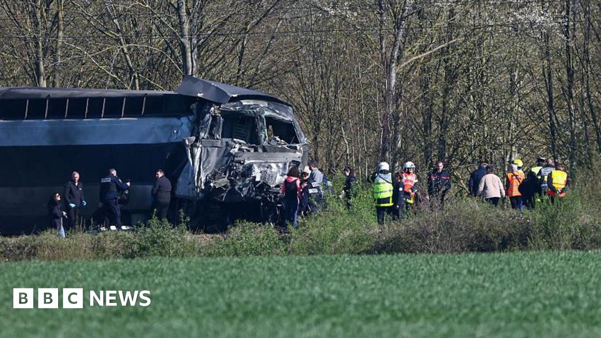 A train is on the left of the image with the front section seriously damaged. Emergency services in hi-vis are on the scene