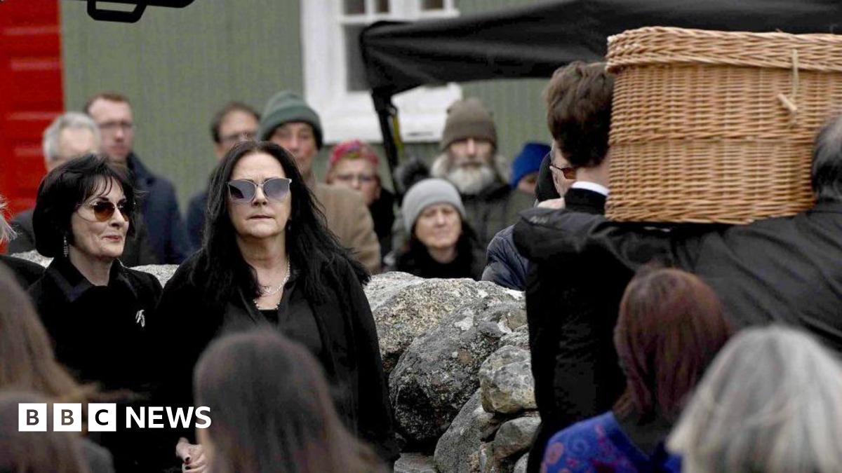 Shows Enya and other mourners at the funeral
