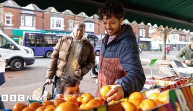 Two women look at the price of cheese in a supermarket chilled dairy aisle.
