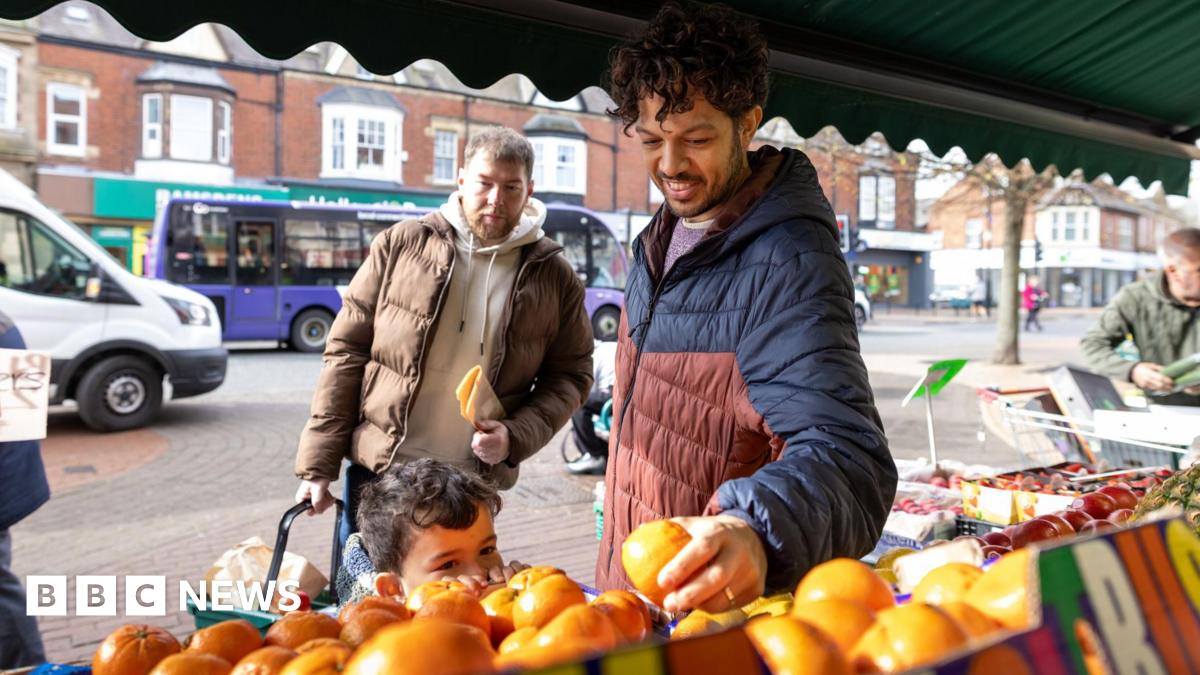 Two women look at the price of cheese in a supermarket chilled dairy aisle.