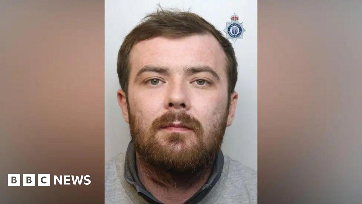 A mugshot of Sean Garner, who has a brown beard and is wearing a grey sweatshirt.