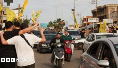 Two men on motorcycles ride among traffic, as people make victory signs and fly yellow Hezbollah flags, in Nabatieh, Lebanon (17/04/26)