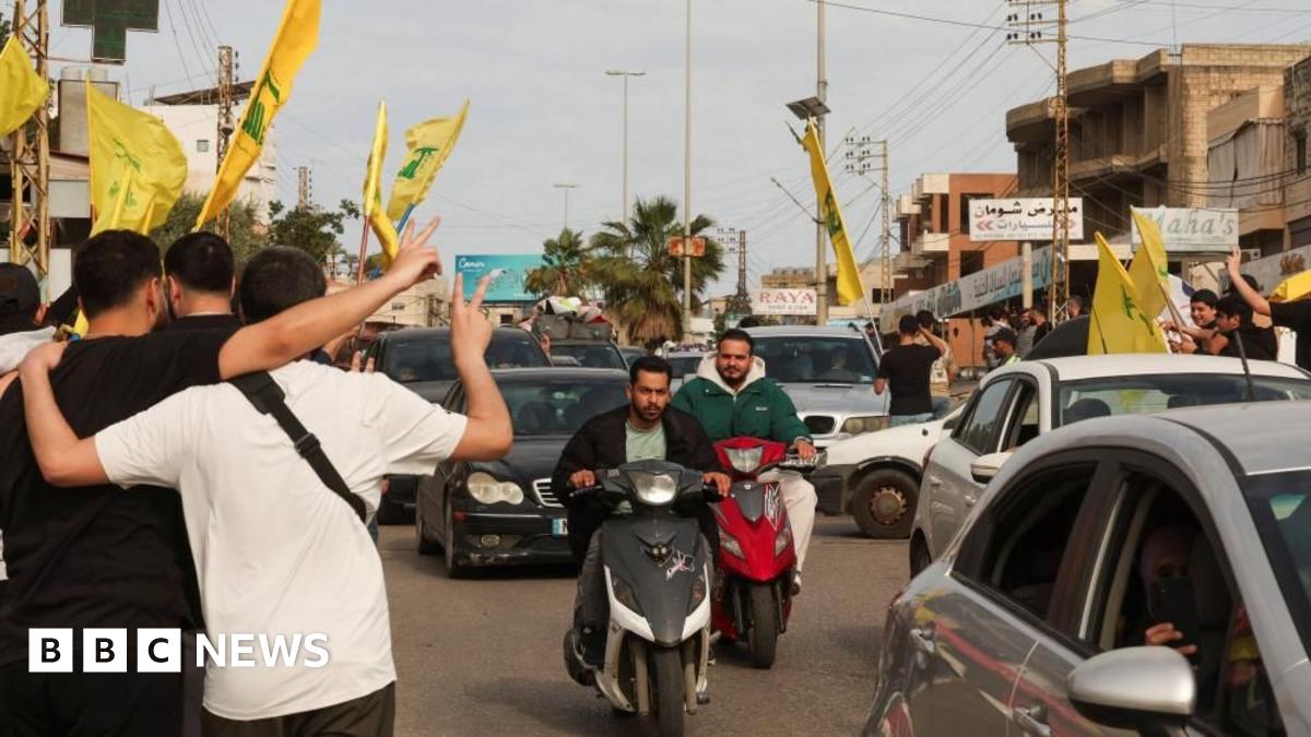 Two men on motorcycles ride among traffic, as people make victory signs and fly yellow Hezbollah flags, in Nabatieh, Lebanon (17/04/26)