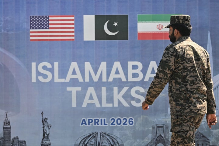A Pakistani Ranger walks past a billboard for the U.S.-Iran peace talks in Islamabad on April 12, 2026. U.S. President Donald Trump announced a U.S. blockade on vessels calling at Iranian ports after the two countries failed to reach a deal.