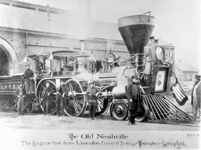 Historical photo of "The Old Nashville" train, used for Lincoln's funeral, with people standing around it. Large portrait of Lincoln on the front