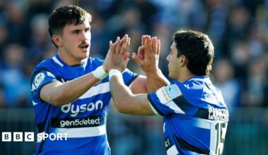 Ewan Richards (left) holds both hands up with palms wide to clap with Santiago Carreras (right)
