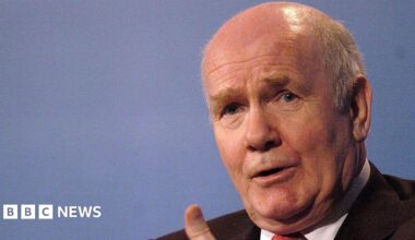 Close up shot of John Reid talking as he gestures with his hands.