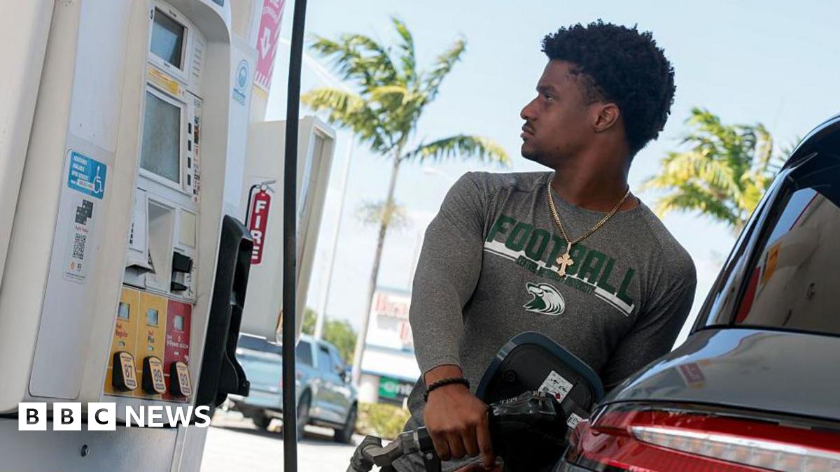 A man looks at the price meter while refuelling his car at a petrol station