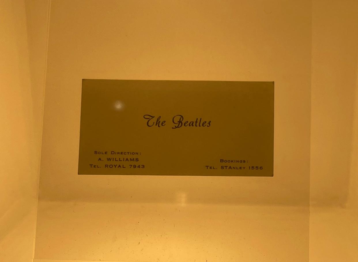 Plaque in a display case with text listing The Beatles' sole direction and booking contact numbers