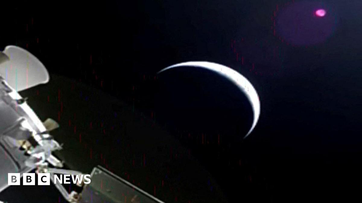 A slightly grainy image from Orion showing a planet - perhaps the moon, as a sliver with most of it in darkness, and part of Orion in the corner.