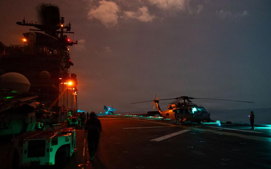 Lights shine on the helicopter on the flight deck.