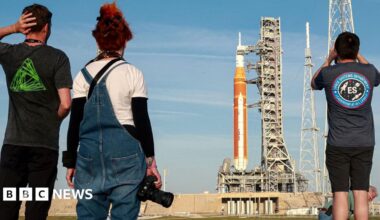Employees from the Johnson Space Center hold signs along Brantly Avenue near Ellington Field as they gather to send off the Artemis II astronauts ahead of their mission to the moon in Houston, Friday, March 27, 2026.
