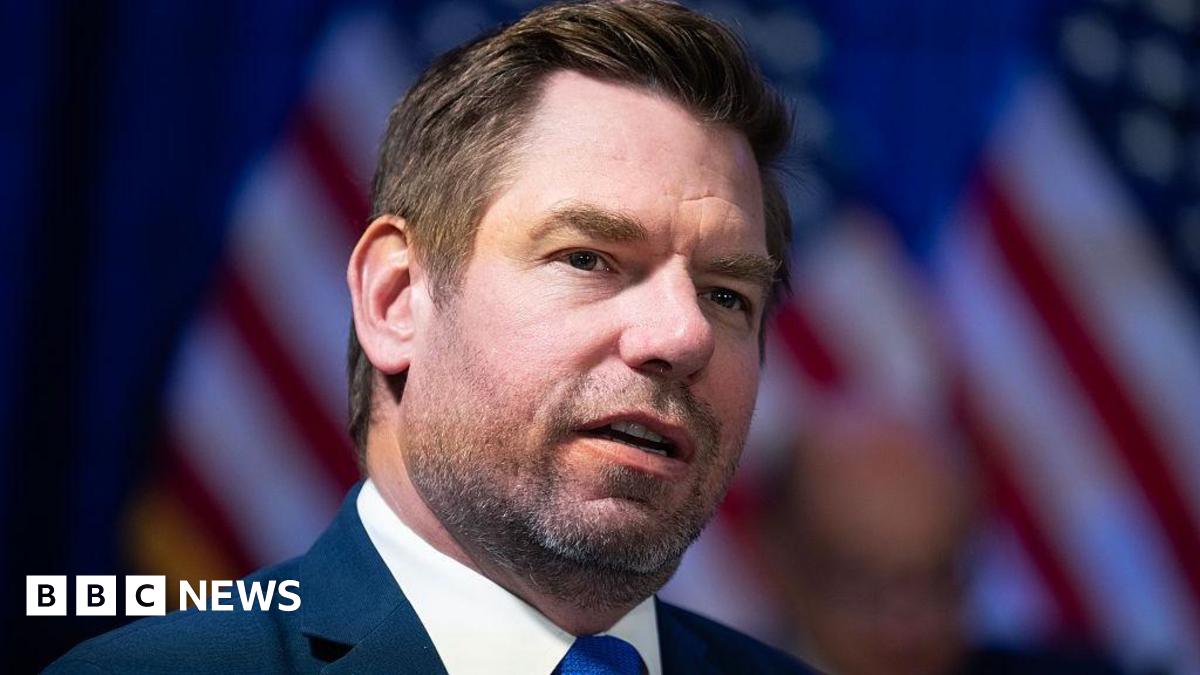 Swalwell seen in January 2026, wearing a blue tie and a pin on his label