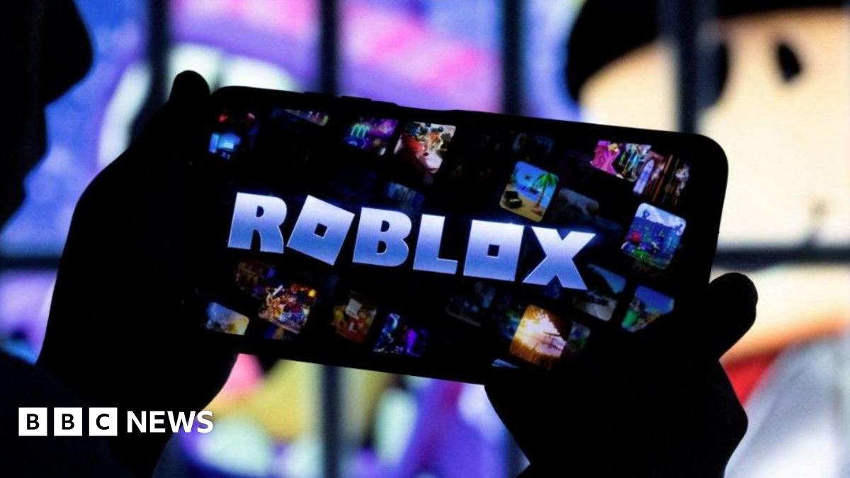 A pair of hands are holding up an iPhone which has the word Roblox in block capital letters on the screen.