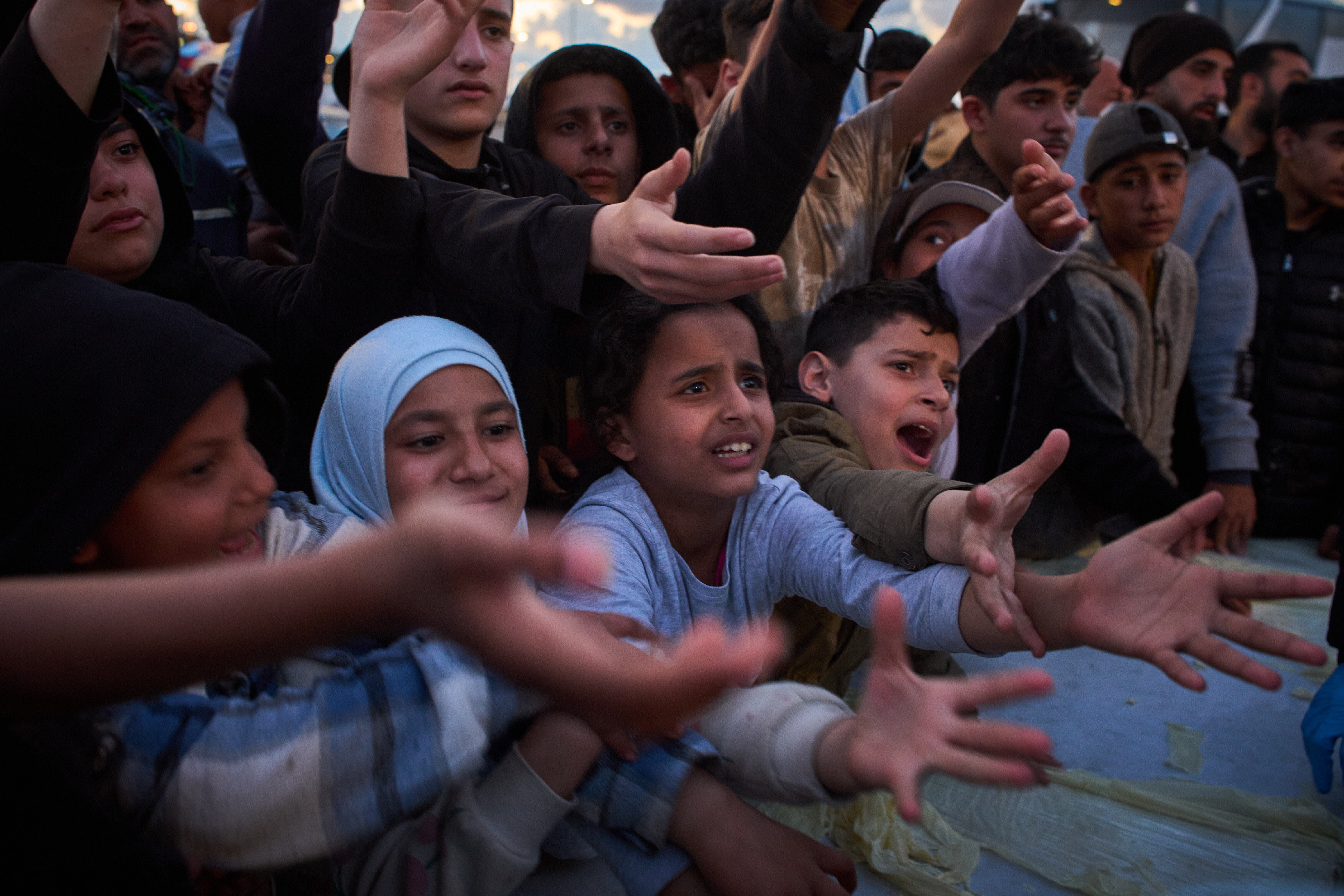 Displaced people wait to receive donated food after fleeing Israeli bombardment in southern Lebanon