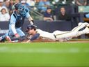 Milwaukee Brewers' Brice Turang, right, scores ahead of the tag by Toronto Blue Jays catcher Tyler Heineman, left, on a sacrifice fly hit by Luis Rengifo during the fourth inning of a baseball game, Thursday.
