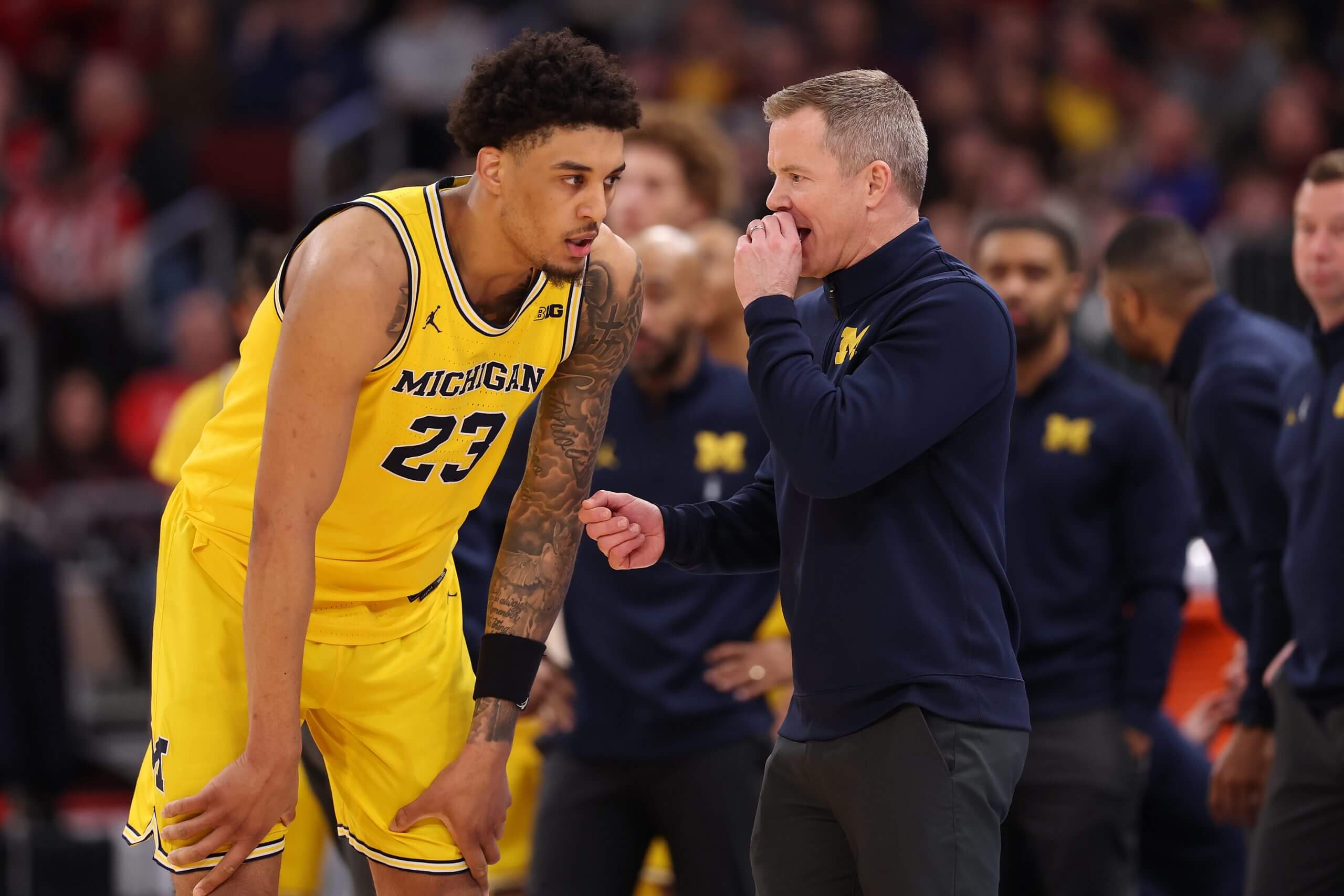 Yaxel Lendeborg bends down with his hands on his knees as he talks with coach Dusty May in a game against Wisconsin in the Big Ten tournament.