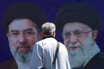 A man walks past a banner with pictures of Iran’s slain supreme leader, Ayatollah Ali Khamenei, and his son and successor, Mojtaba Khamenei, along a street in Tehran on April 15.