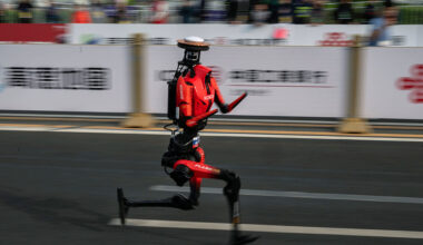 The fastest humanoid robot, an H1made by Honor, runs beside human runners at the start on its way to winning the Beijing Humanoid Half Marathon.