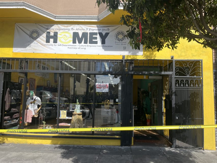 A storefront with a "HOMEY" banner above the entrance and yellow caution tape blocking the front. Clothing and accessories are visible through the windows.