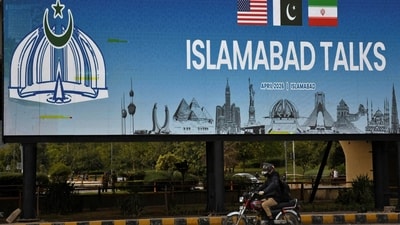 A man rides his motorbike past a billboard installed alongside a road as Pakistan prepares to host the US and Iran for peace talks, in Islamabad. (Reuters Photo)