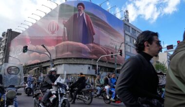 Pedestrians look at a destroyed building within the Grand Hosseiniyeh, with the mosque visible in the background, which officials at the site say was hit by U.S.-Israeli airstrikes Tuesday, in Zanjan, Iran, Saturday, April 4, 2026. (AP Photo/Francisco Seco)