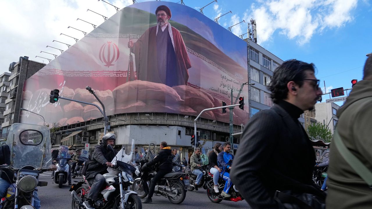 Pedestrians look at a destroyed building within the Grand Hosseiniyeh, with the mosque visible in the background, which officials at the site say was hit by U.S.-Israeli airstrikes Tuesday, in Zanjan, Iran, Saturday, April 4, 2026. (AP Photo/Francisco Seco)