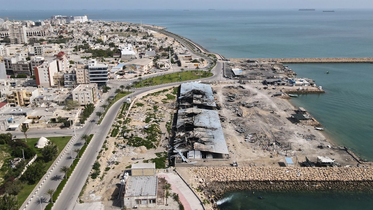 Backdropped by ships in the Strait of Hormuz, damage, according to local witnesses caused by several recent airstrikes during the U.S.-Israel military campaign, is seen on a fishing pier in the port of Qeshm island, Iran, Monday, April 13, 2026. (AP Photo/Asghar Besharati)