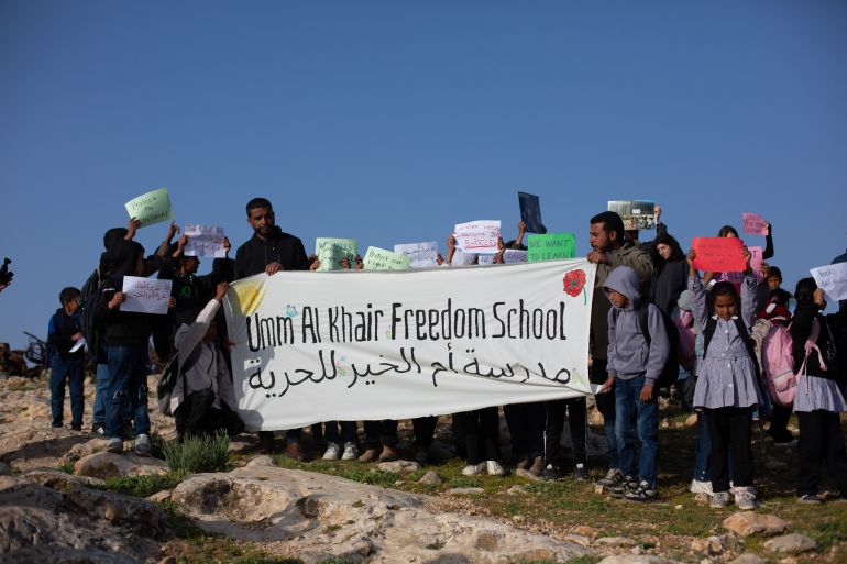 Khalil and Tareq hold banner with kids [Jacob Lazarus/Al Jazeera]