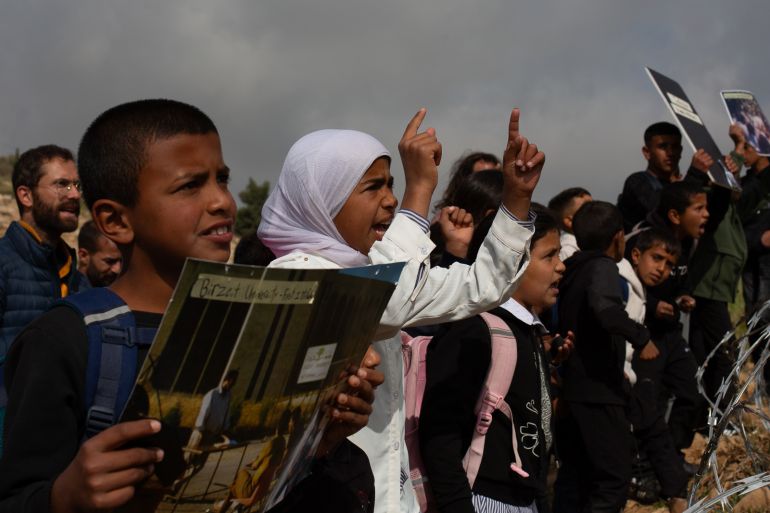 Kids at fence at Umm al-Khair telling soldiers to open road [Steven Davidson/Al Jazeera]