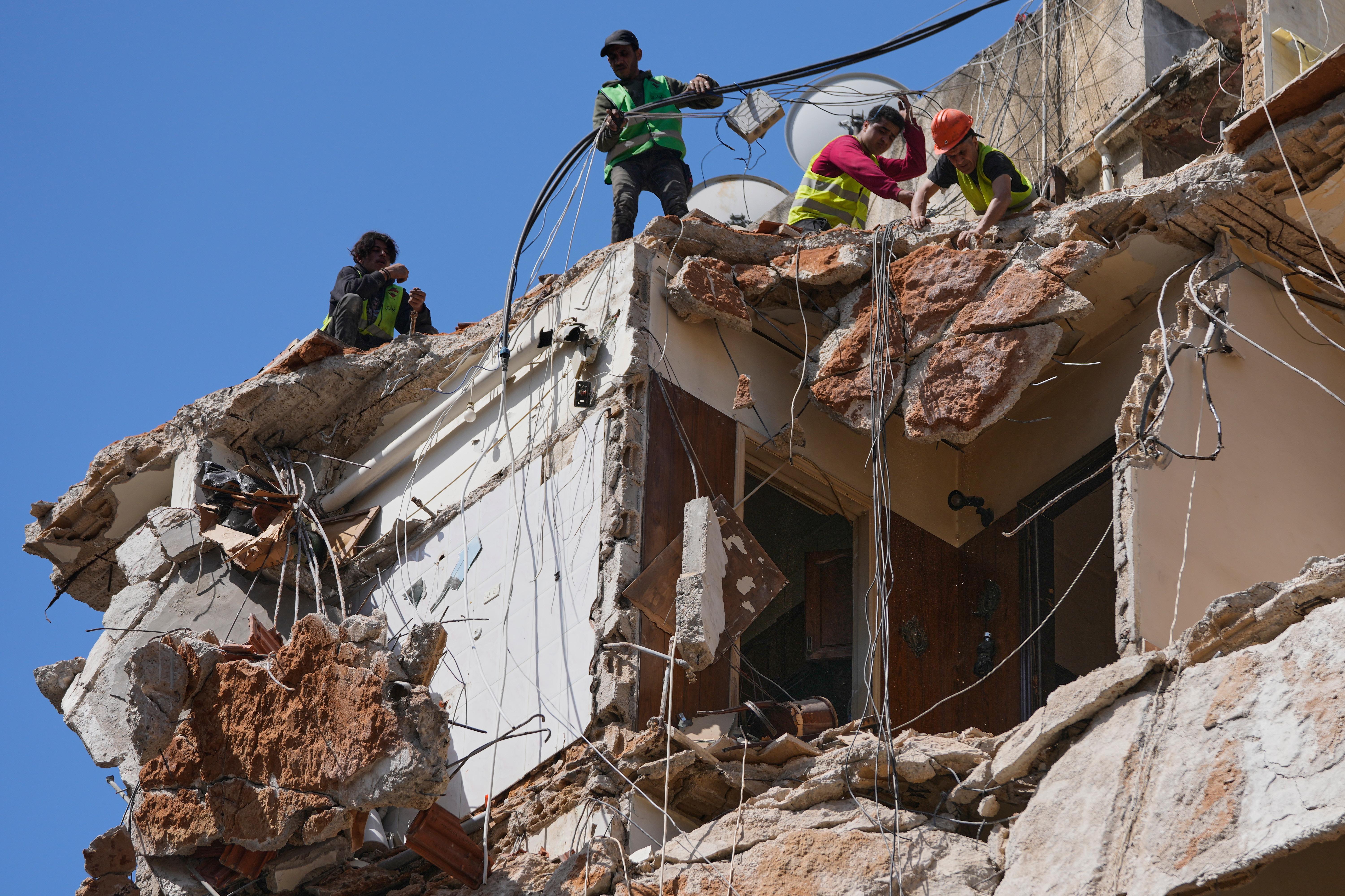 Workers remove the rubble as rescuers search a building hit in an Israeli airstrike in Beirut.