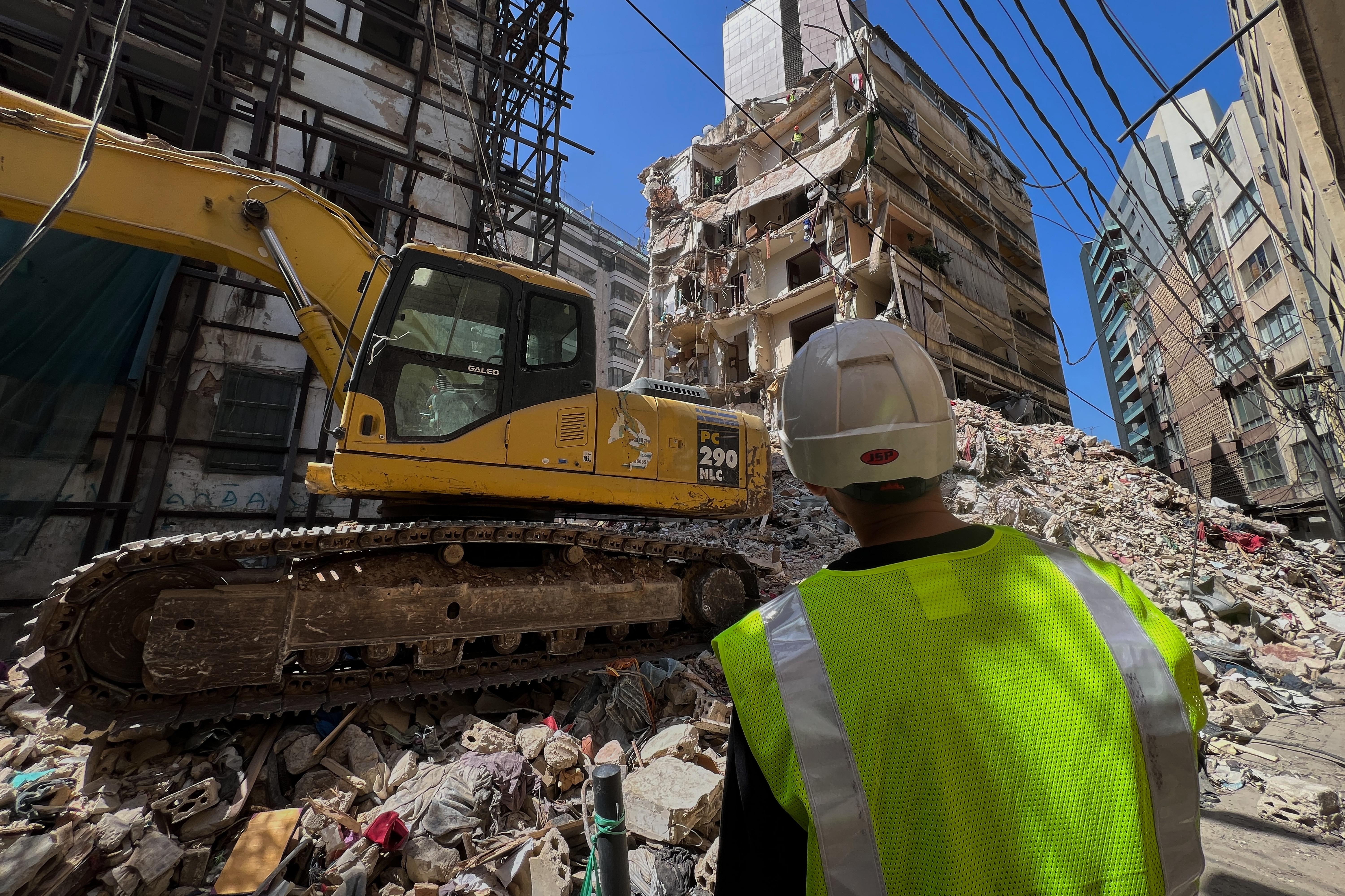 Workers remove the rubble as rescuers search a building hit in an Israeli airstrike in Beirut.