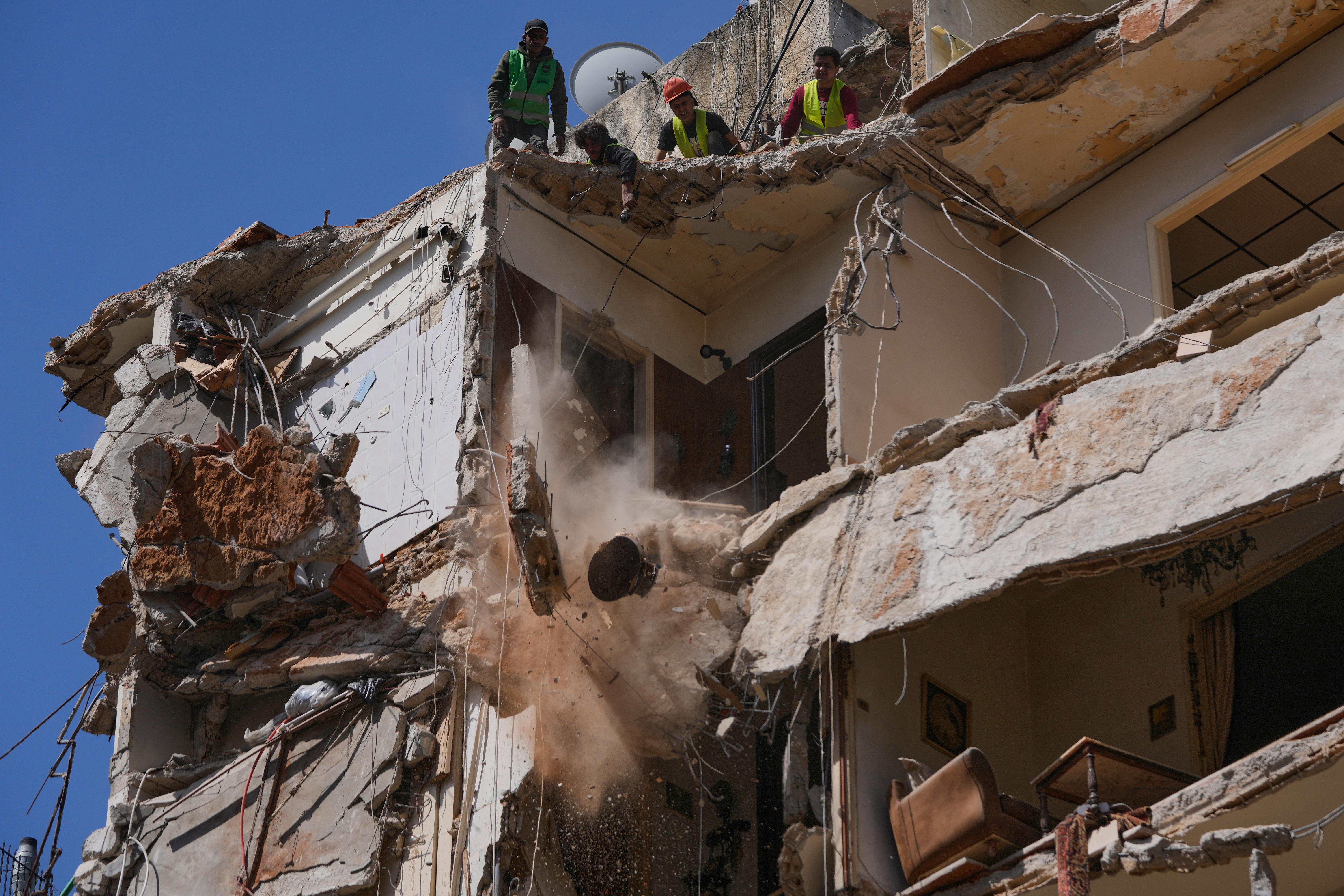Workers remove the rubble as rescuers search a building hit in an Israeli airstrike in Beirut.