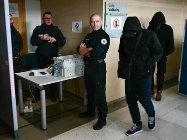 Men with hidden faces walk by police.
