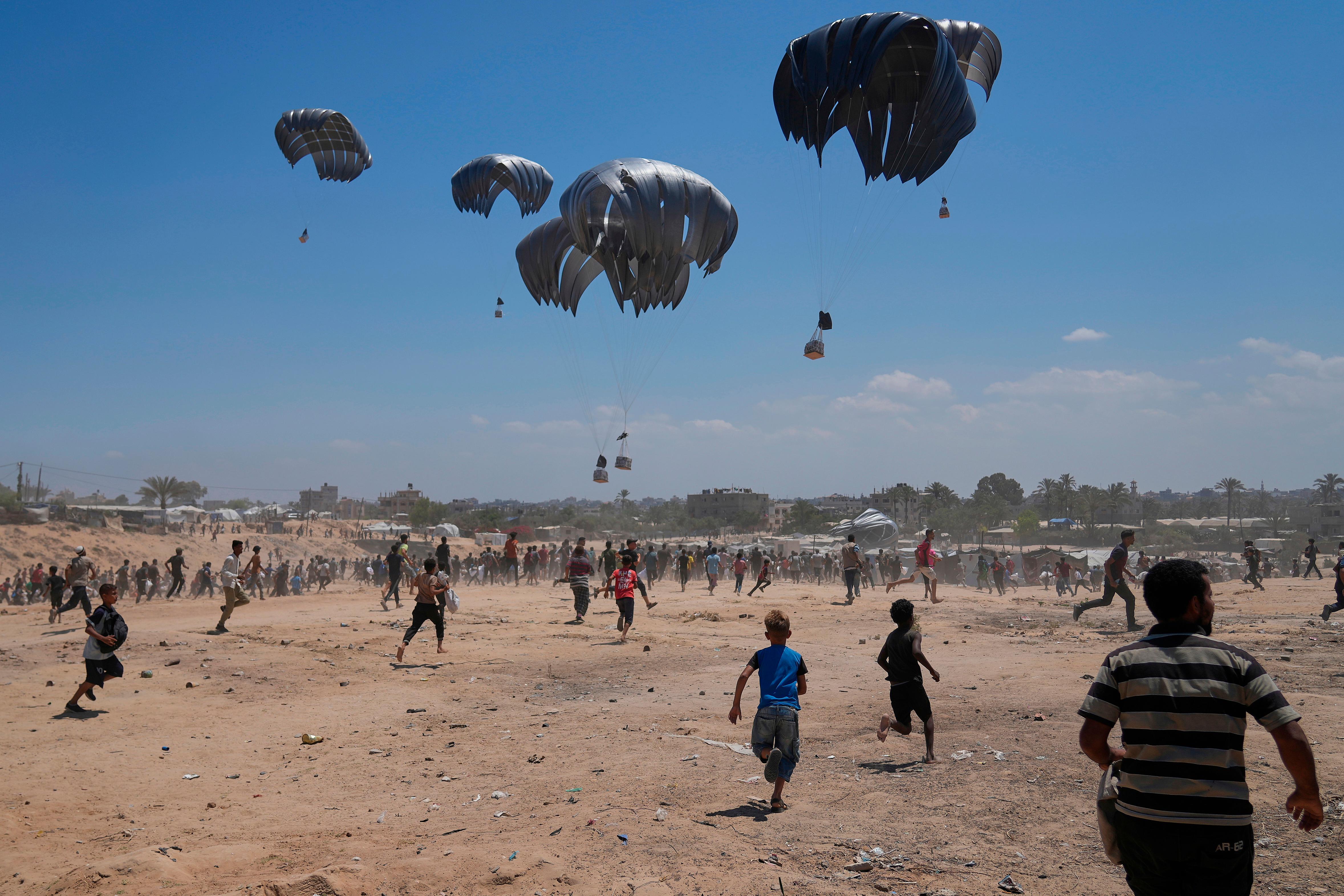 Palestinians rush to collect humanitarian aid airdropped by parachutes into Zawaida.