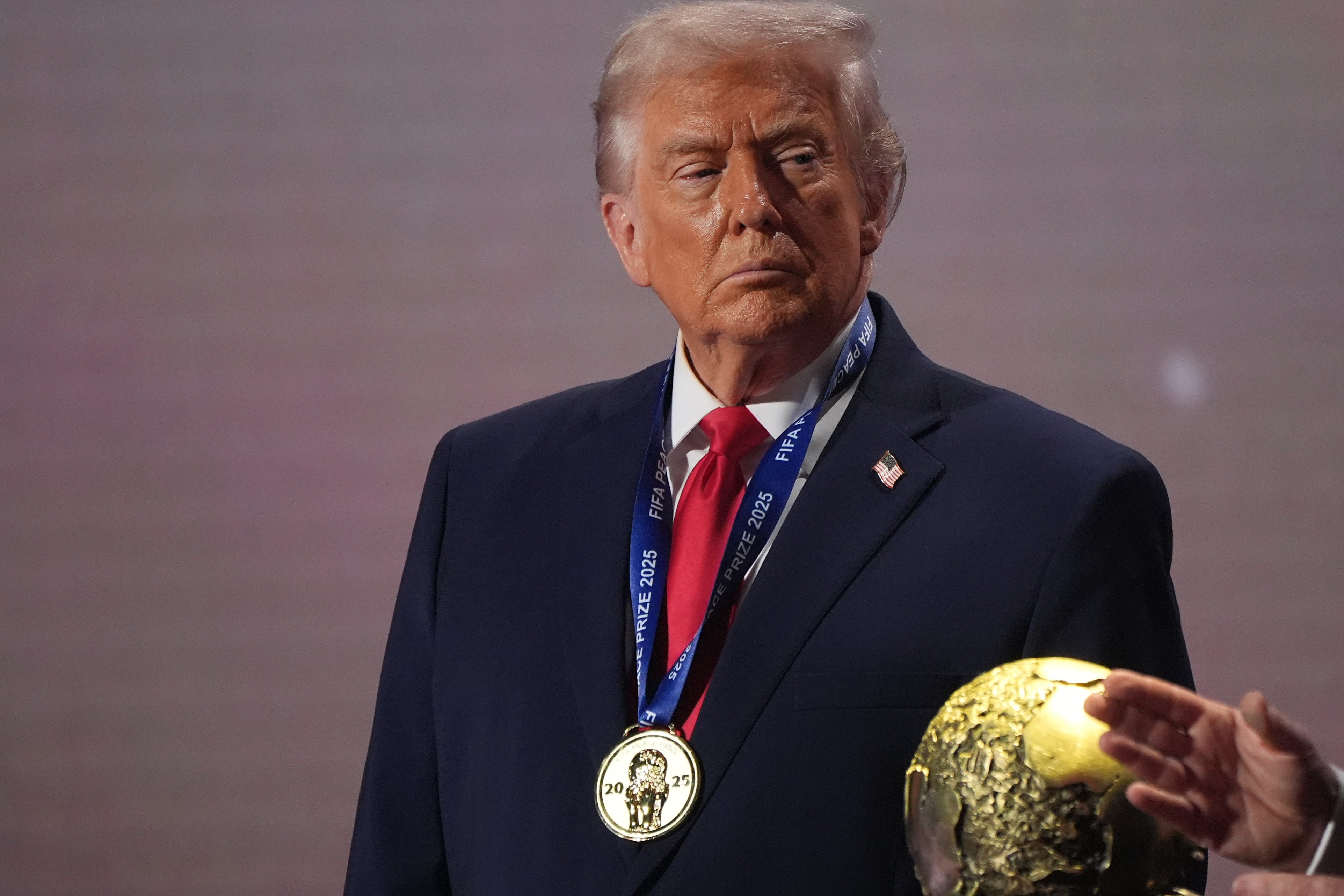 President Donald Trump stands on stage next to the FIFA World Cup after receiving the FIFA Peace Prize during the draw for the 2026 soccer World Cup at the Kennedy Center in Washington, Dec. 5, 2025