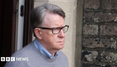Mandelson standing outside his London home looking glum.
