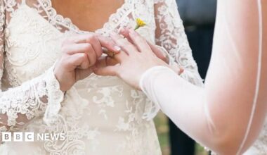 A ring is being placed on someone's finger at a wedding ceremony.