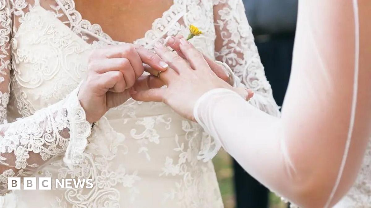 A ring is being placed on someone's finger at a wedding ceremony.