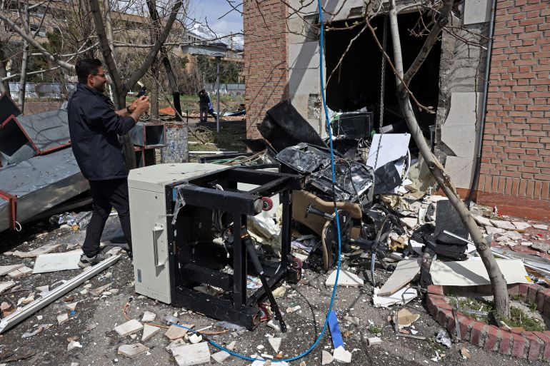 A man takes pictures of the destroyed study equipments lying amid the debris of a damaged building of the Shahid Beheshti University following a strike, in Tehran on April 4, 2026.