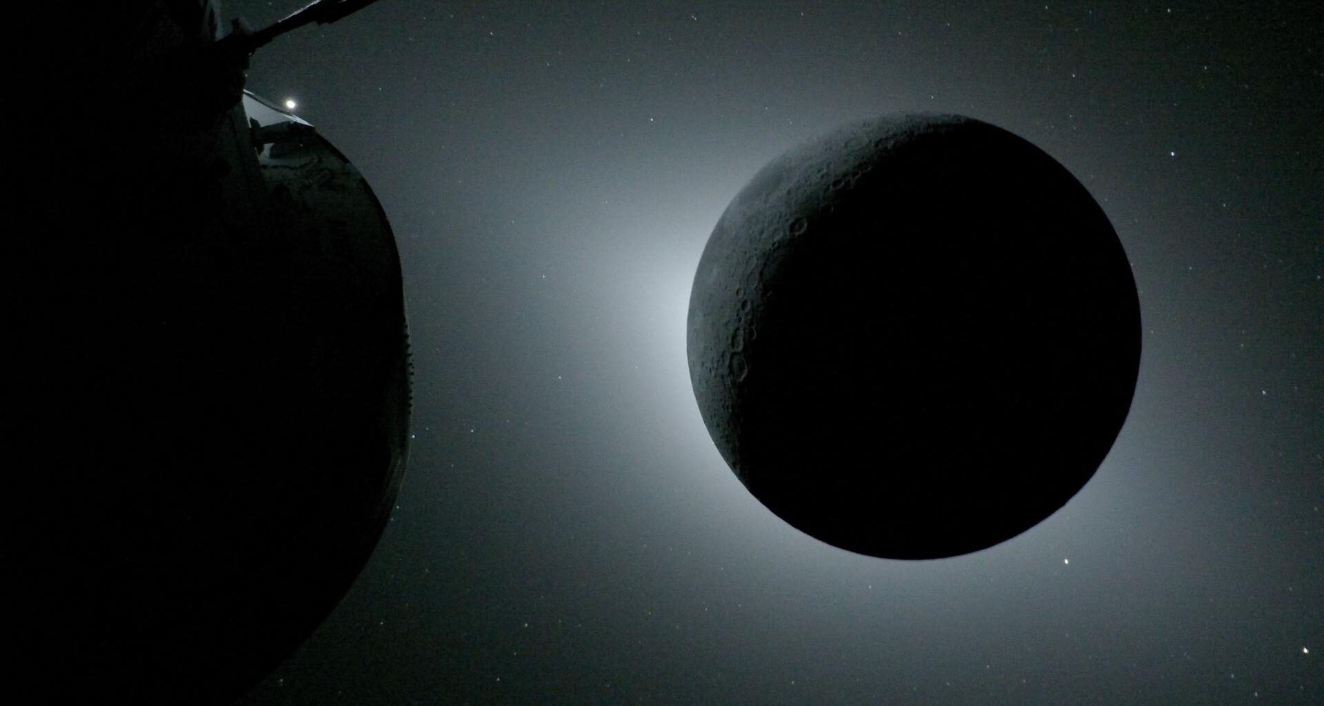 The Moon, backlit by the Sun during a solar eclipse, is photographed by NASA’s Orion spacecraft on April 6, 2026, during the Artemis II mission. Orion is visible in the foreground on the left. Earth is reflecting sunlight at the left edge of the Moon, which is slightly brighter than the rest of the disk. The bright spot visible just below the Moon’s bottom right edge is Saturn. Beyond that, the bright spot at the right edge of the image is Mars.