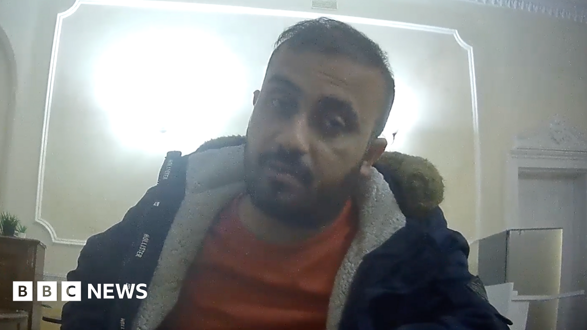 Zahid Hasan Akhand, a bearded man wearing a fleece jacket and jumper and sitting at a desk, in a picture taken by an undercover reporter