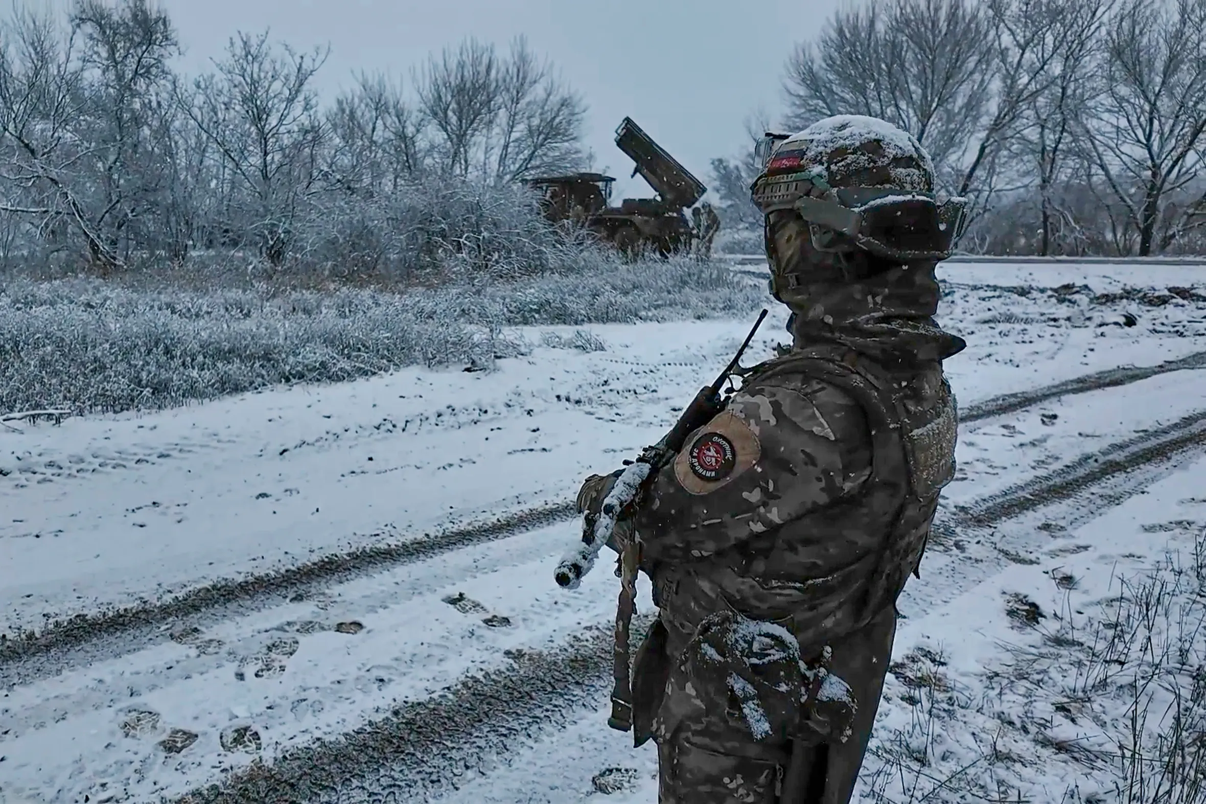 Russian soldier guards a Grad multiple rocket launcher in a snowy landscape.