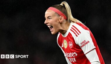Chloe Kelly slides on her knees in celebration while wearing Arsenal's red and white kit and a red headband