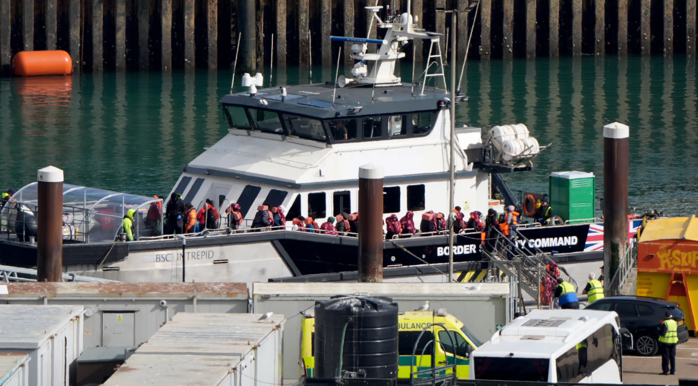 A Border Security Command vessel, BSC Intrepid, carrying a group of migrants wearing life vests, arrives at the Dover, Kent compound.