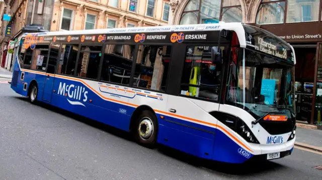 A blue and white McGill's bus driving down a street